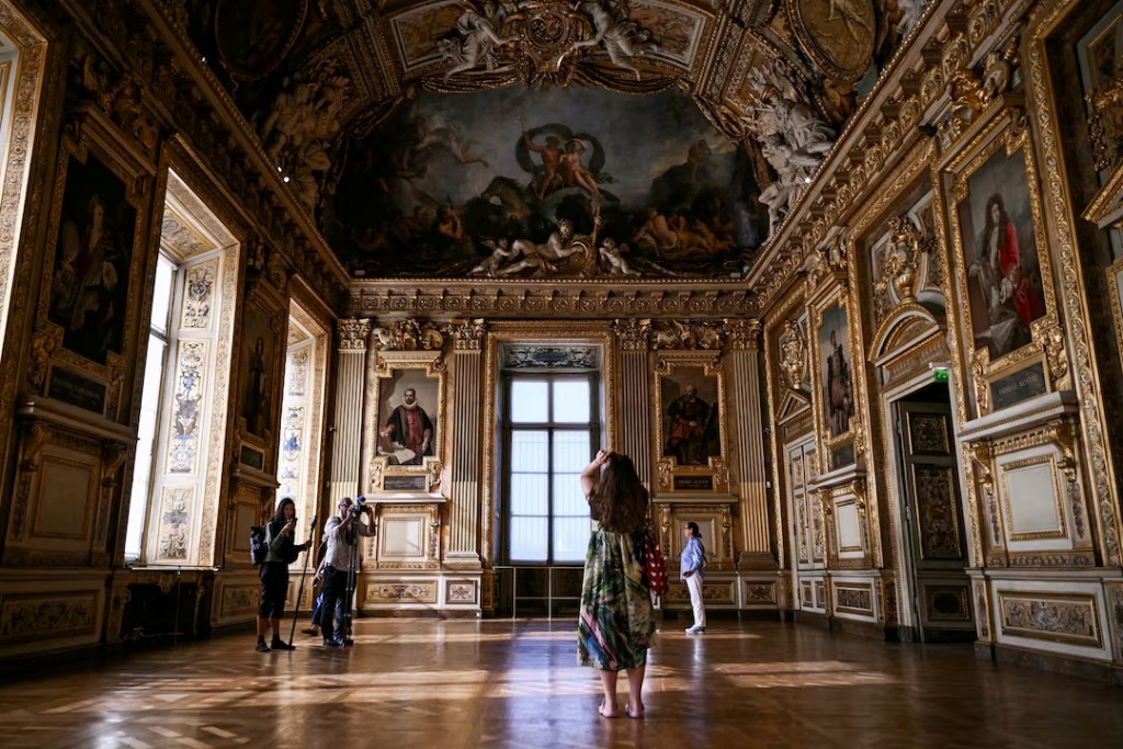 Visitors stand near the window which was broken in the 2025 heist in which French crown jewels were stolen from the Apollo Gallery (Galerie d'Apollon), during the gallery's reopening to the public, at the Musee du Louvre in Paris, France, July 22, 2026. LOU BENOIST/Pool via REUTERS