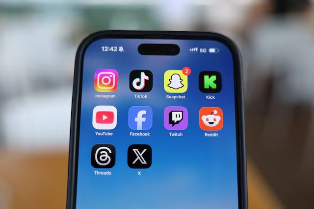 Instagram, TikTok, Snapchat, Kick, YouTube, Facebook, Twitch, Reddit, Threads and X applications are displayed on a mobile phone in this picture illustration taken on December 9, 2025. REUTERS/Hollie Adams/Illustration