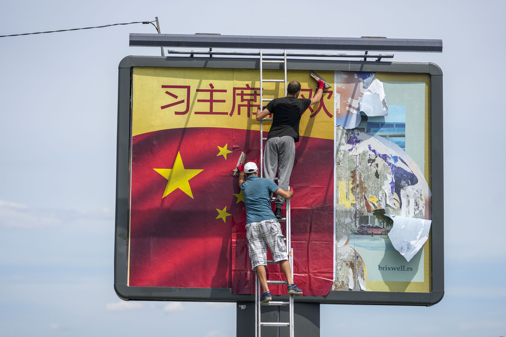 Workers stick a Chinese national flag on a billboard in Belgrade. AP Workers stick a Chinese national flag on a billboard in Belgrade. AP