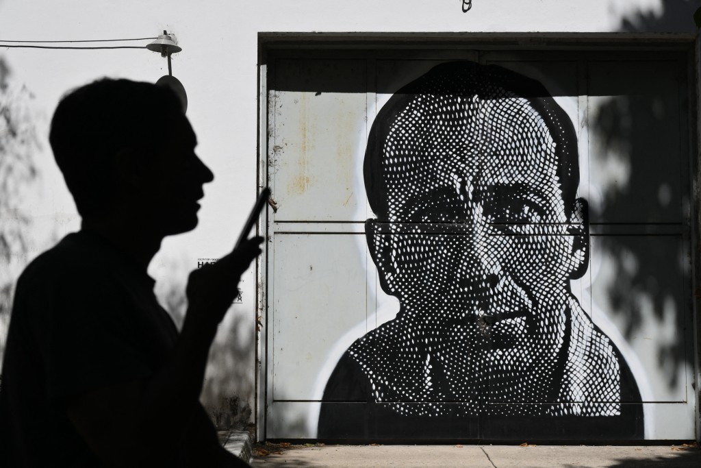 Photo by LUIS ROBAYO / AFP  A man walks past a photo of Haroldo Conti, who disappeared on May 5, 1976 during the military dictatorship (1976-1983), displayed at the former clandestine detention center of the Navy School (ESMA) in Buenos Aires on March 18, 2026.