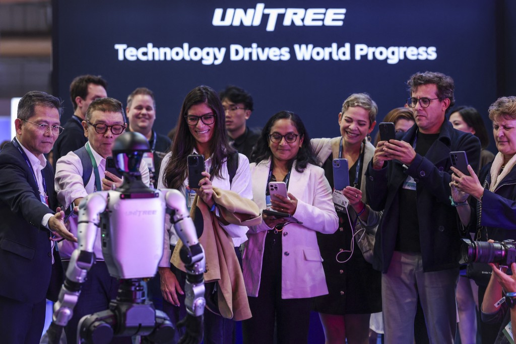 Photo by PATRICIA DE MELO MOREIRA / AFP  People take pictures with their mobile phones during a performance of the Unitree robot at the Web Summit at Parque das Nacoes in Lisbon, on November 11, 2025.