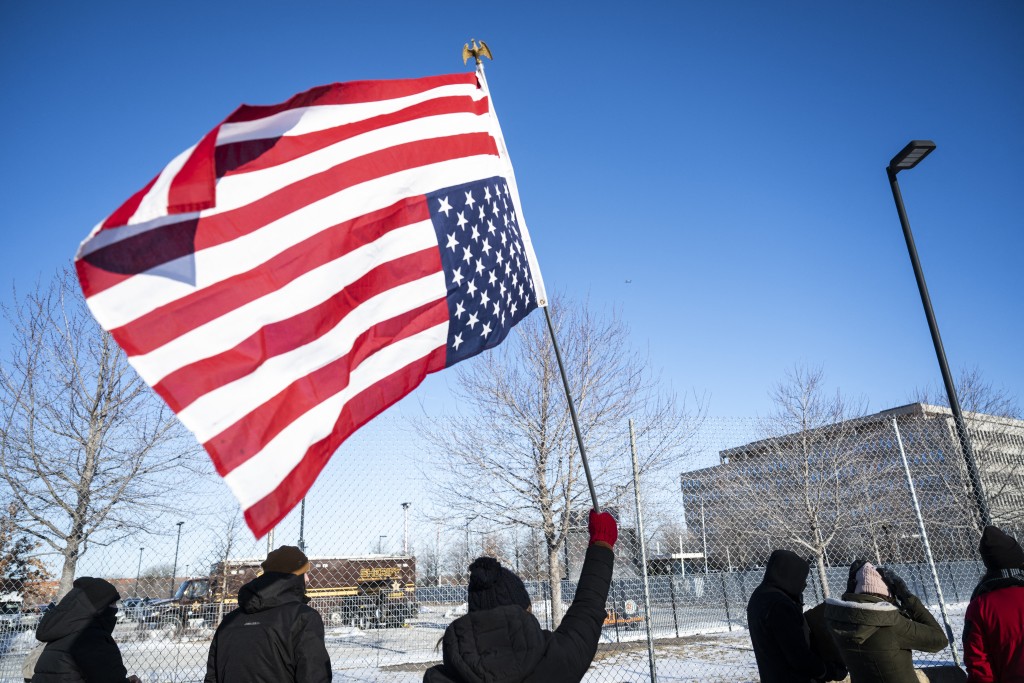 A protester holds a US flag high on a road near the entrance to the Bishop Henry Whipple Federal Building in Minneapolis, Minnesota on January 30, 2026.  Photo by ROBERTO SCHMIDT / AFP
