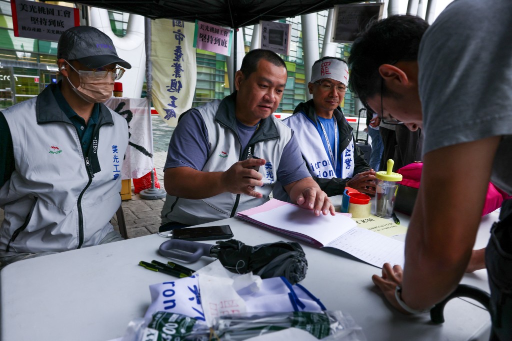 Photo by I-HWA CHENG / AFP  A Micron Technology worker signs a document to decide whether to support or reject the company's latest proposal outside of the company building in Taoyuan on October 22, 2026.