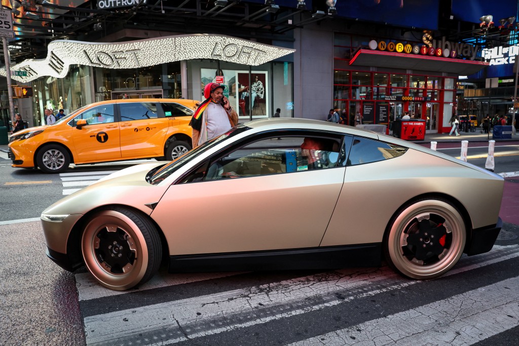 A Tesla Cybercab drives in Times Square following an appearance in New York City, U.S., October 27, 2025.  REUTERS