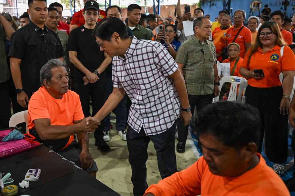 Photo by JAM STA ROSA / AFP  Philippine President Ferdinand Marcos Jr (R) interacts with a tricycle driver during the distribution of a fuel subsidy in Manila on March 17, 2026.