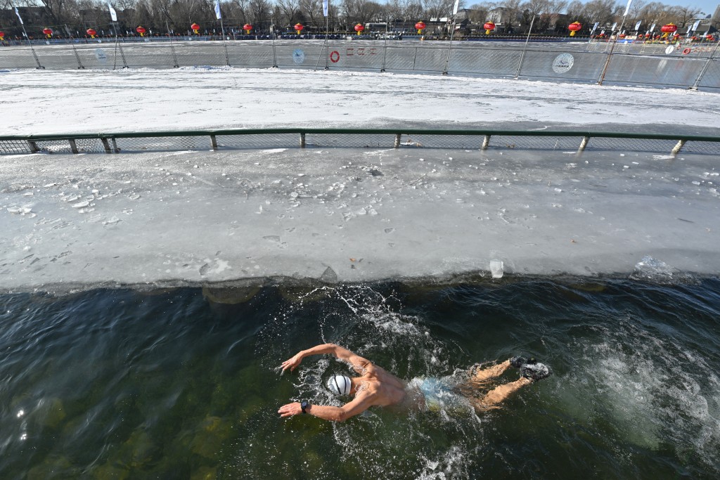 Photo by ADEK BERRY / AFP  Zhang Xin, a winter swimming enthusiast swims at the Houhai Lake of the Shichahai scenic area in Beijing on January 20, 2026.