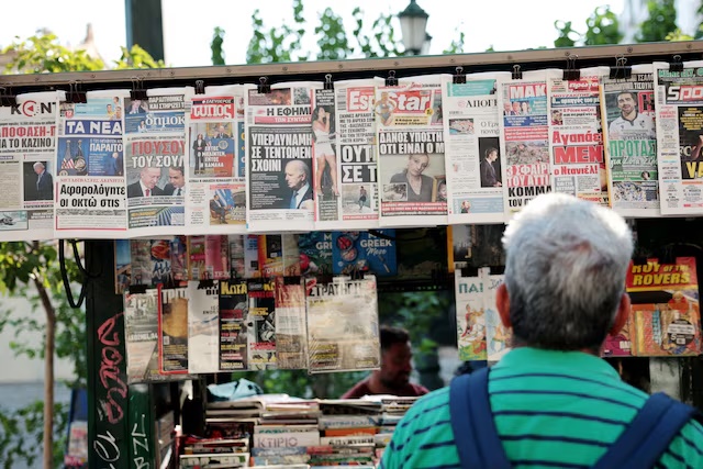 A man looks at newspaper headlines at a kiosk, a day after U.S. President Joe Biden announced that he is dropping his reelection bid, in Athens, Greece, July 22, 2024. REUTERS/Louiza Vradi/File Photo