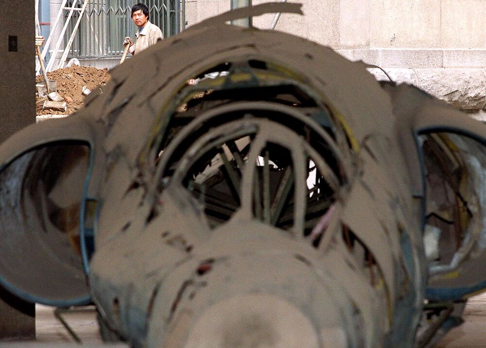 A Chinese construction worker (back-L) pauses while digging a trench 01 May 2001 next to an old, shot-down United States U2 spy plane on display at Beijing's Military Museum. (AFP) 