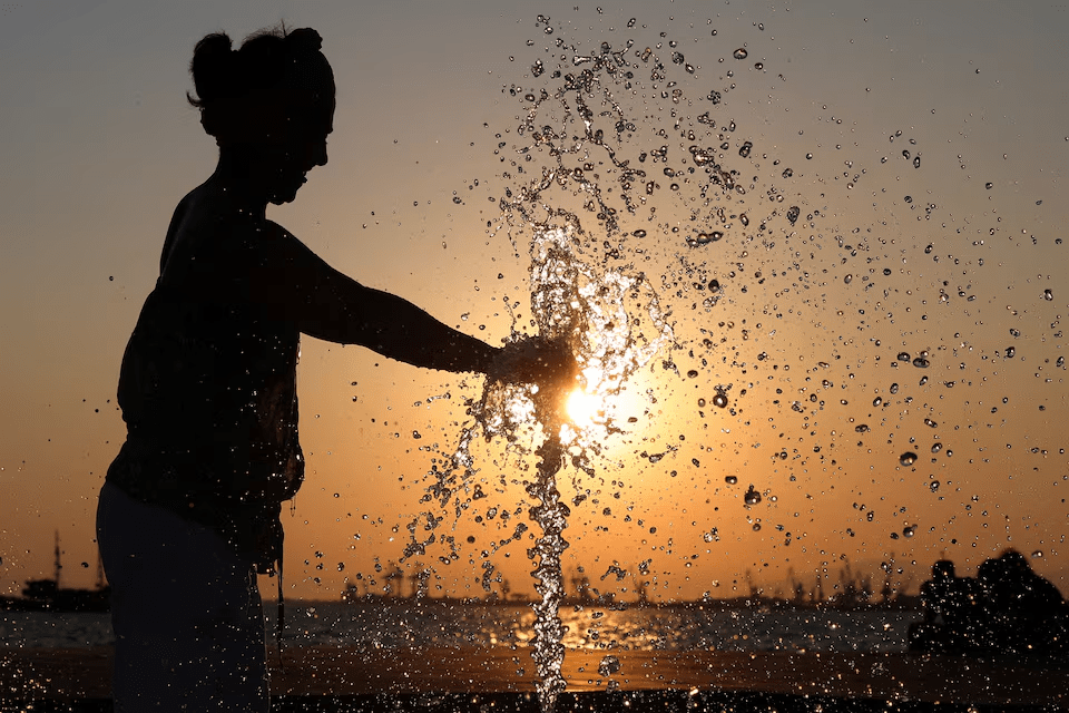 A woman plays in a fountain during a hot day in Thessaloniki, Greece, July 21, 2025. REUTERS/Alexandros Avramidis