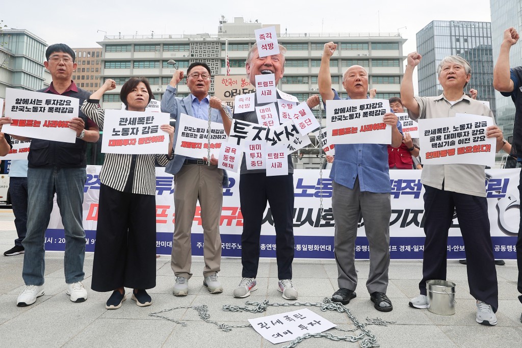 This photo taken on September 9, 2025 shows protestors, including one wearing a mask depicting US President Donald Trump, standing near the US Embassy in Seoul, as they rally in support of South Korean workers who were detained in an immigration raid in the US state of Georgia. South Koreans made up the majority of people arrested at a Hyundai-LG battery plant under construction in Georgia last week, according to immigration agents. (Photo by YONHAP / AFP)