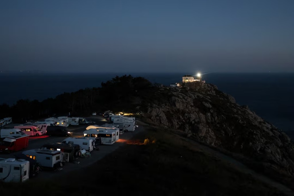 Tourists in campervans and motorhomes wait for solar eclipse in front of Cape Fisterra lighthouse the day before the solar eclipse, on the Costa da Morte ("Coast of Death"), once considered the end of the world and a traditional destination for pilgrims completing the Camino de Santiago, in northwestern Spain, August 11, 2026. REUTERS/Nacho Doce