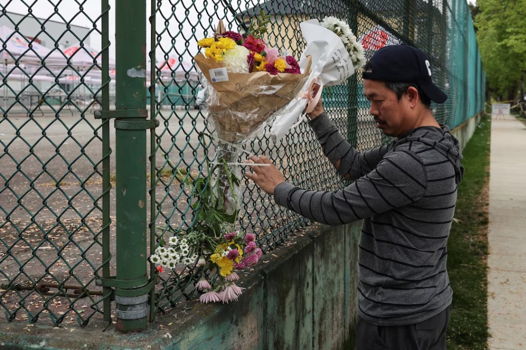 A man places tributes on a fence after a vehicle was driven into a crowd at a Lapu Lapu day block party in Vancouver. REUTERS/Chris Helgren