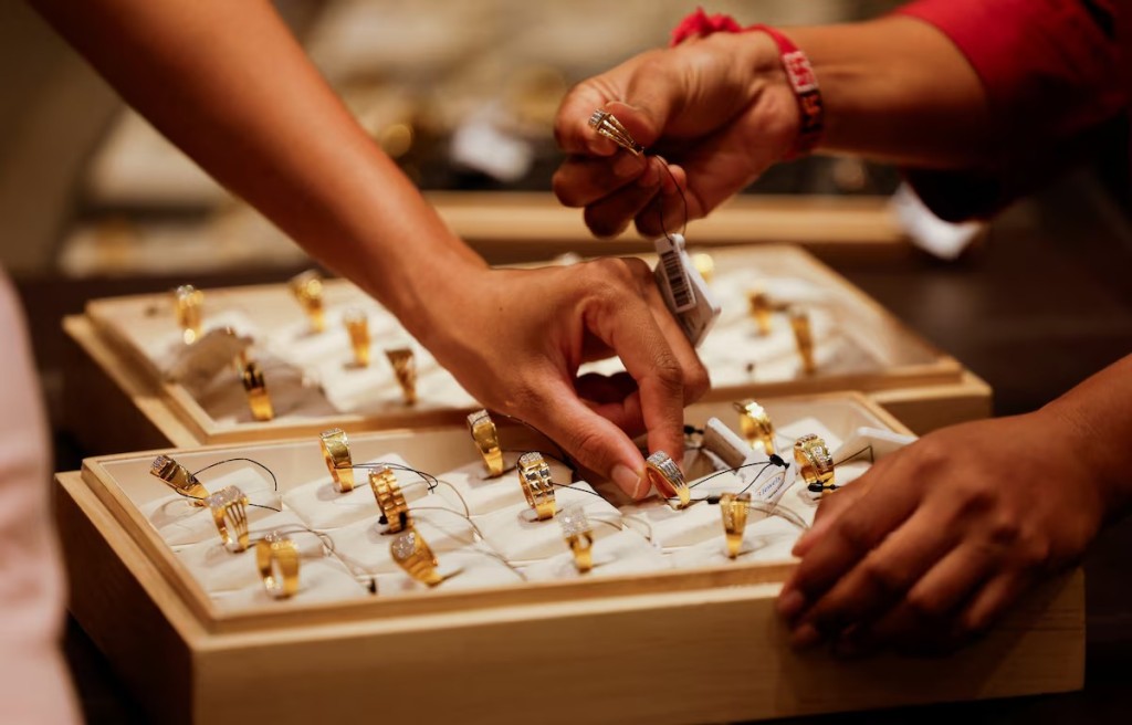A salesperson shows a gold ring to customers at a jewellery showroom in Ahmedabad, India, October 8, 2025. REUTERS