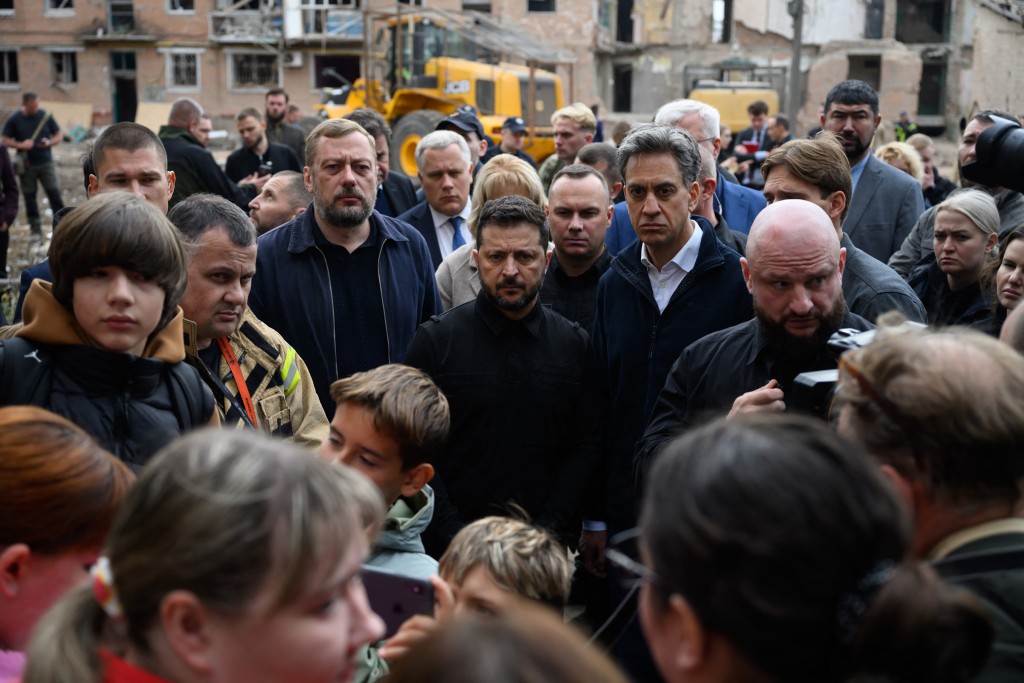This handout photograph taken and released by Ukrainian Presidential Press Service on October 8, 2026, shows Ukraine's President Volodymyr Zelensky (C) and Britain's Foreign Secretary Ed Miliband (C-R) speaking with local residents during their visit to a flattened five-storey apartment a day after a Russian missile attack in Pryluky, Ukraine. (Photo by Handout / UKRAINIAN PRESIDENTIAL PRESS SERVICE / AFP) / RESTRICTED TO EDITORIAL USE - MANDATORY CREDIT "AFP PHOTO / UKRAINIAN PRESIDENTIAL PRESS SERVICE" -
