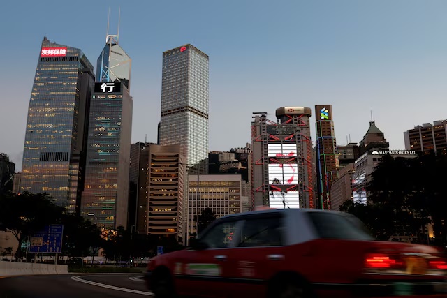 A taxi drives in front of skyscrapers at the central business district in Hong Kong, China August 17, 2021. Picture taken August 17, 2021. REUTERS/Tyrone Siu/File Photo