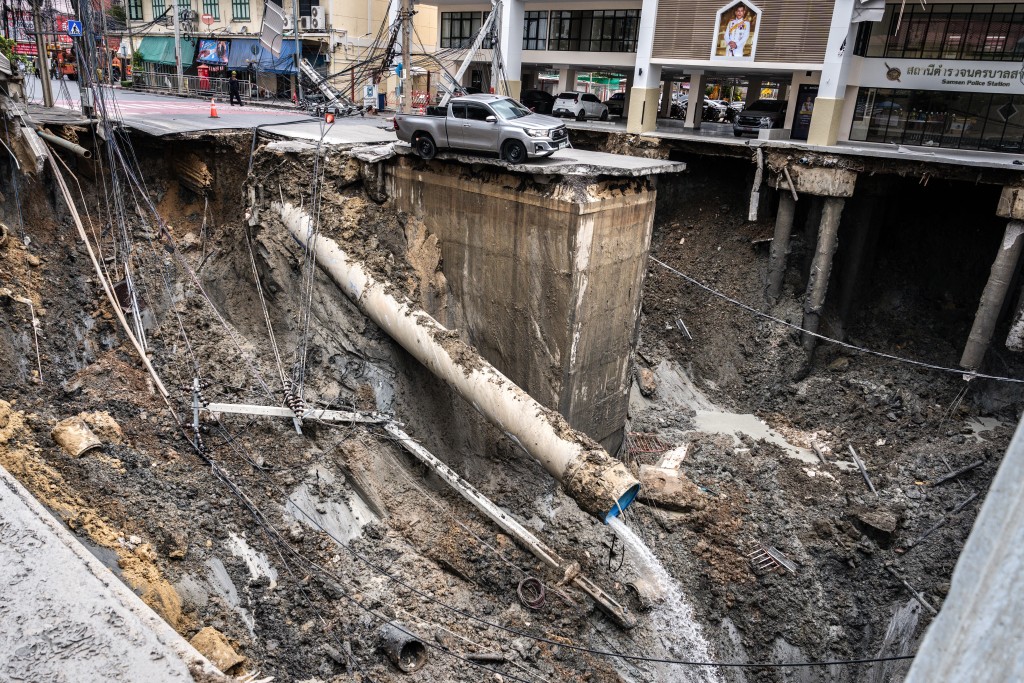 A vehicle is seen on the edge of a hole in the ground after a road collapsed near a hospital in Bangkok on September 24, 2025. A portion of a busy road in Thailand's capital caved in early on September 24, leaving a hole dozens of meters deep in front of a main hospital and forcing people nearby to evacuate. (Photo by Chanakarn Laosarakham / AFP)