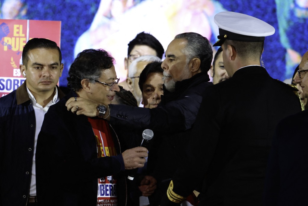 Photo by JOHN VIZCAINO / AFP. Colombia's President Gustavo Petro (2nd L) is embraced by Minister of the Interior Armando Benedetti during a rally at Bolivar Square in Bogota on October 24, 2025.