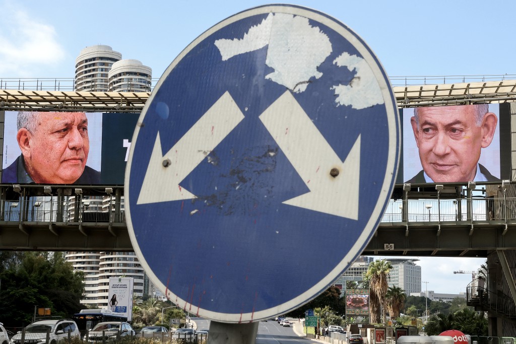 Photo by JACK GUEZ / AFP A road sign stands in front of a large billboard featuring Israel's Prime Minister Benjamin Netanyahu (R) of the Likud party and former military chief and leader of the centrist Yashar party, Gadi Eisenkot, in Ramat Gan on October 20, 2026.