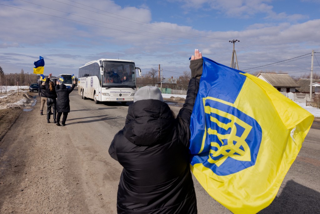 Photo by TETIANA DZHAFAROVA / AFP. People with Ukrainian flags welcome Ukrainian prisoners of war (POW) following a prisoner exchange in the Chernihiv region on March 6, 2026, amid the Russian invasion of Ukraine.