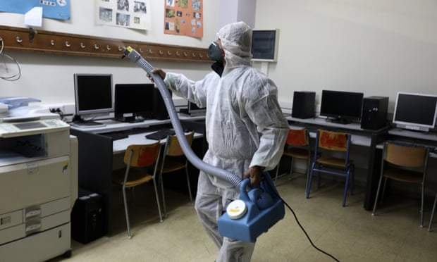 A worker sprays disinfectant inside a classroom at a high school in Athens. A worker sprays disinfectant inside a classroom at a high school in Athens.