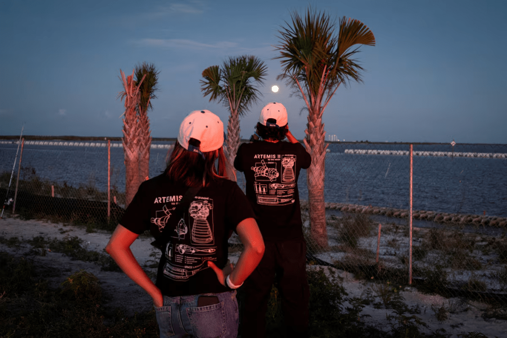 A man uses his phone to take photos of the moon after the launch of the next-generation moon rocket, the Space Launch System (SLS) rocket and the Orion crew capsule, part of NASA's Artemis II lunar flyby mission, from NASA's Kennedy Space Center, in Titusville, Florida, U.S., April 1, 2026. REUTERS/Marco Bello