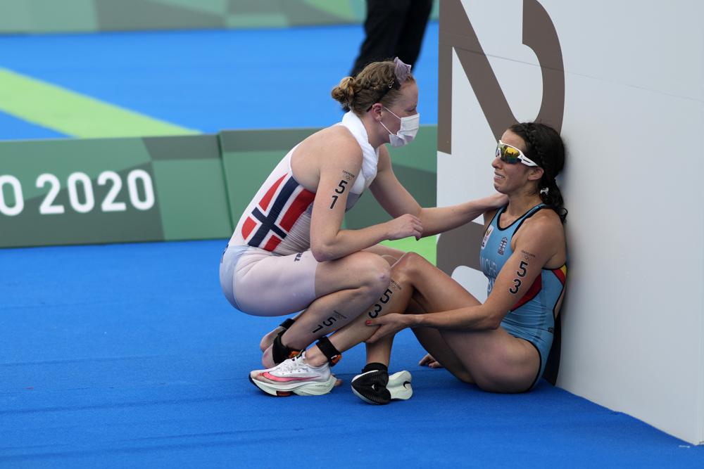  In this July 27, 2021, file photo, Claire Michel of Belgium is assisted by Lotte Miller of Norway after the finish of the women's individual triathlon competition at the 2020 Summer Olympics, in Tokyo, Japan. 