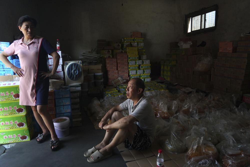 Yu Ruiping, left, and her husband Lu Jinlin, middle, rest in a family warehouse with pickled vegetables that they salvaged from the floods in Xinxiang in central China's Henan Province, Monday, July 26, 2021. 