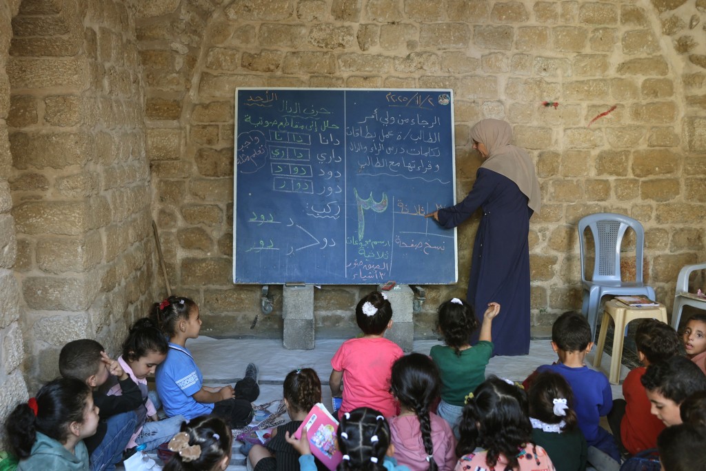 Photo by OMAR AL-QATTAA / AFP  Palestinian children attend a class in the historic "Al-Kamaliya al-Othmanya" school in Gaza City's Old Town, as part of a volunteer initiative organized by displaced teachers, in Gaza City on November 2, 2025.
